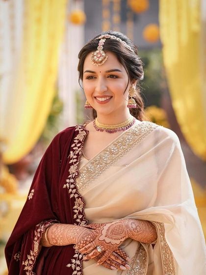 The bride's full look, showing her elegant saree and the simple yet stunning hairstyle. The messy twisting ponytail is a modern and chic option for today's bride.