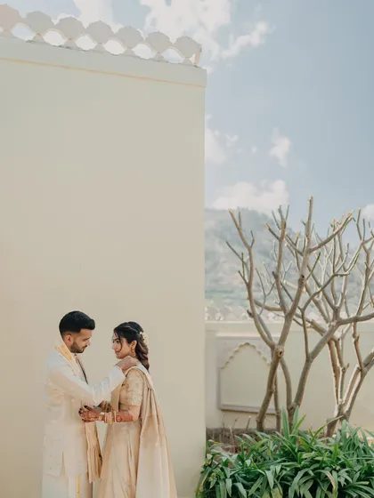 A minimalist and artistic portrait of the couple against a plain wall, with the natural landscape in the background.