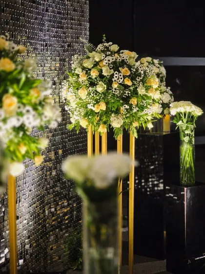 A close-up of the lush floral arrangements used to frame the sequin photo booth, showing the mix of white and yellow roses against the shimmering backdrop.