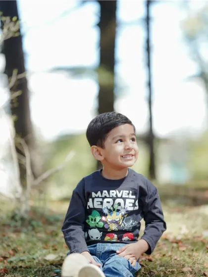 A beautiful portrait of a young boy looking up at the sky, his face lit by the sun. The natural setting of an outdoor shoot provides the perfect backdrop for these thoughtful, candid moments.