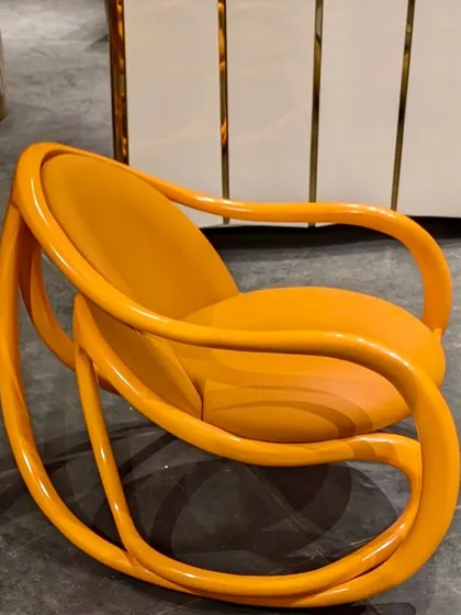 A modern interpretation of our rocking chair, finished in a vibrant, high-gloss orange lacquer. This piece adds a playful and bold pop of color to any space.