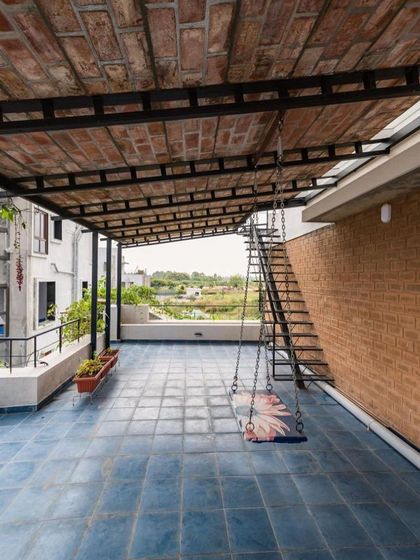 The spacious terrace of the Samvrruddhi home, featuring a swing and a roof made of reclaimed bricks. This outdoor living area offers a peaceful retreat with views of the surrounding landscape.