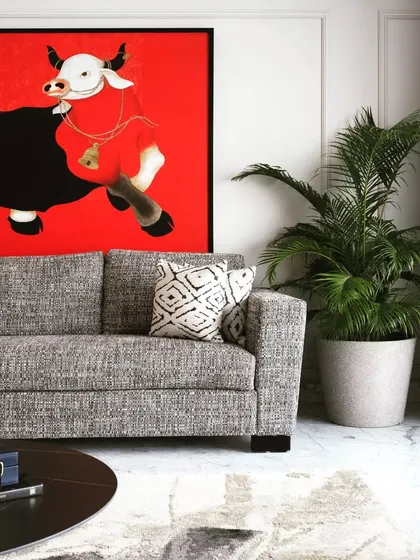 A close-up of the main sofa and the statement art. The textured grey fabric of the sofa provides a perfect neutral base for the vibrant red in the painting.