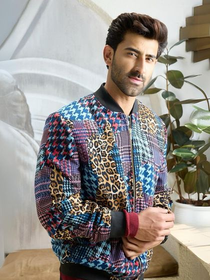 The multi-patterned jacket, seen in a relaxed setting, shows its versatility as a statement piece that can elevate any casual look.