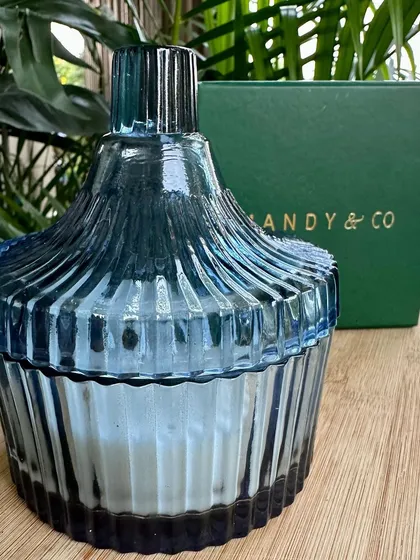 The delicious vanilla double-wicked ribbed glass candle, closed, showing off its beautiful blue glass container.