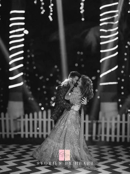 A romantic moment on the dance floor. The black and white photo beautifully captures the couple's connection, with the string light decor creating a magical bokeh effect in the background.