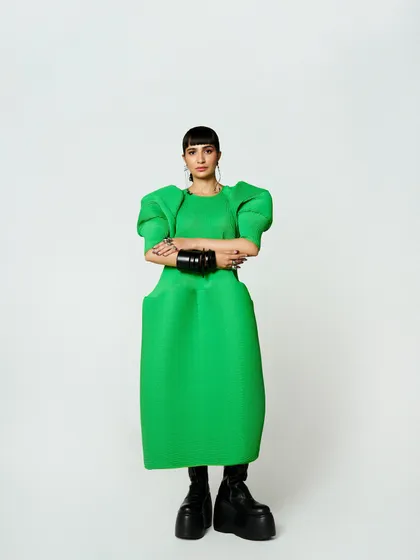 Attending Vogue's Forces of Fashion event in a striking green sculptural dress. This look is about making a statement with bold color, unconventional shapes, and powerful accessories.