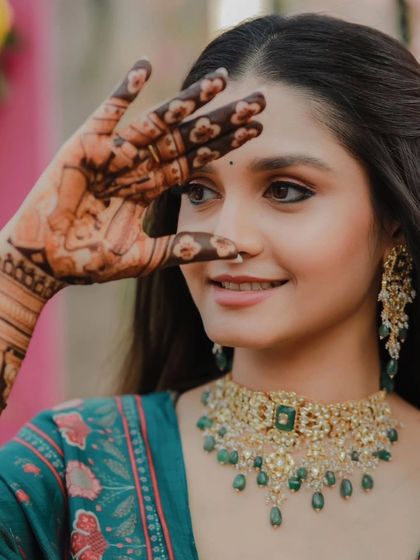 A close-up of a bride's face, with her mehandi-covered hand creating a beautiful frame.