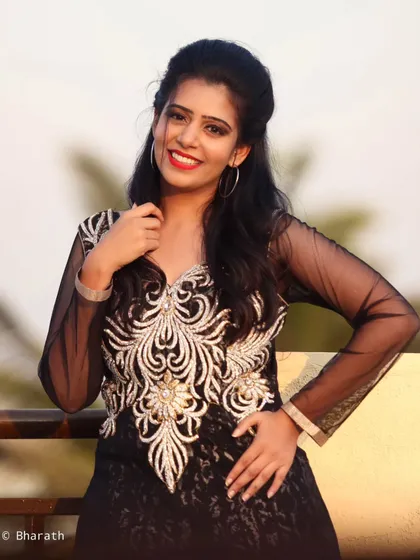 A close-up portrait of the model in the black gown, with a bright smile and direct eye contact.