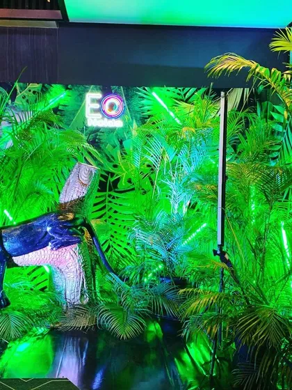 This photo backdrop features a black panther prop emerging from a wall of illuminated green foliage. The use of focused lighting creates a sense of mystery and drama, perfect for a 'wild' themed event.