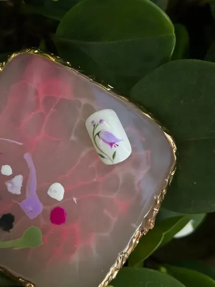 A detailed shot of a hand-painted tulip on a sample nail, showing the delicate brushwork.