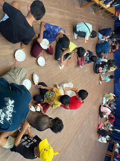 This overhead view shows a large group of students diligently working on their paper plate baskets. It captures the focused energy and scale of our popular summer camp craft activities.