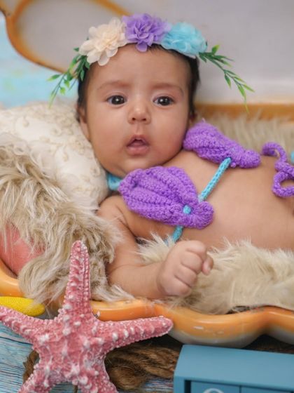 A close-up of the baby mermaid in the seashell. Her curious expression is adorable.