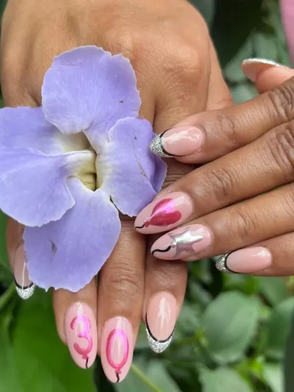 A close-up of the birthday nails, held with a flower to highlight the beautiful design details.
