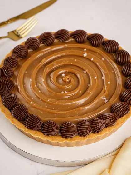 A full view of the Signature Chocolate Pudding Tart with caramel and sea salt. The swirl of caramel and the border of Belgian chocolate ganache make it a work of art.