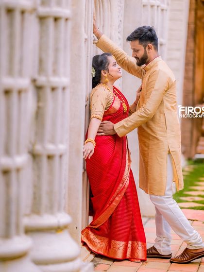 An intimate moment between a couple in traditional attire, framed by white pillars.