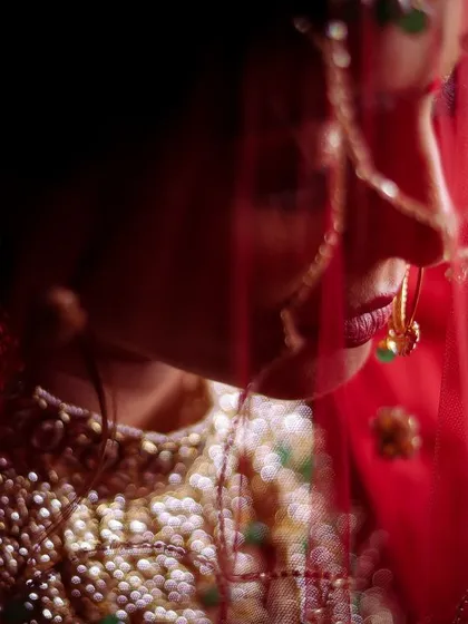 This is an extreme close-up, focusing on the fine details of the bride's veil and nath (nose ring). The shadows create a sense of mystery and elegance, highlighting the traditional elements of her look.