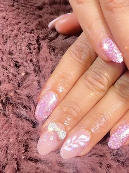 A sweet and sparkly pink glitter set. The accent nails feature a delicate white leaf design and a 3D silver bow.