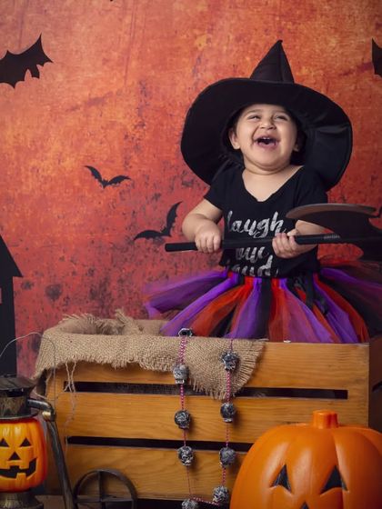 The happiest little witch you'll ever see! She's having a great time with her axe prop in this playful Halloween shoot.