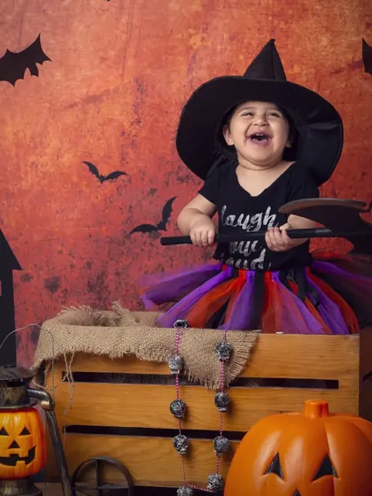 The happiest little witch you'll ever see! She's having a great time with her axe prop in this playful Halloween shoot.