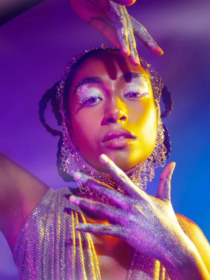 A direct and engaging portrait from the glitter series. The combination of the model's expression and the vibrant, colorful lighting creates a captivating and energetic image.