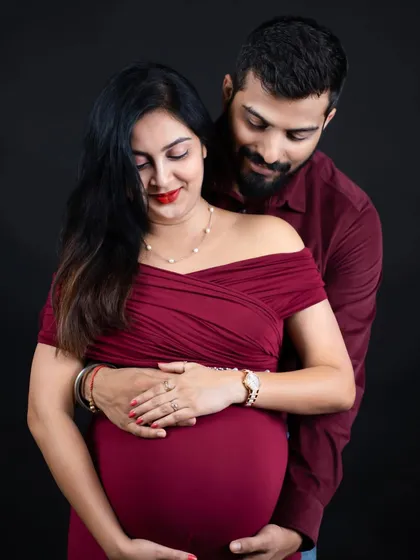 An intimate close-up of a couple. The partner embraces the mom-to-be from behind, both gently holding the baby bump in a moment of shared love.