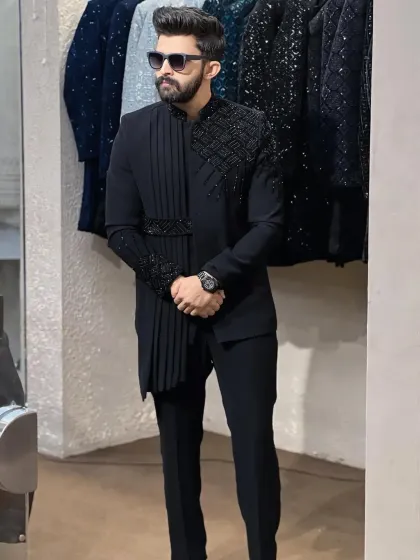 For a modern and fashion-forward look, I designed this black Indowestern set. It features an asymmetrical cut with a pleated drape and geometric beaded embellishments on the shoulder and cuff.