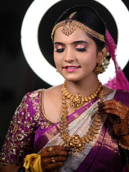 A close-up of Disha's muhurtham look, with soft pink eyeshadow and traditional gold jewellery, framed by a ring light.