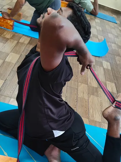 A student uses a strap to work towards Poorna Rajakapotasana (Full King Pigeon Pose). Straps are excellent tools to help bridge the gap between your hands and feet in deep backbends.