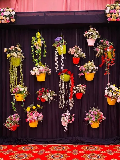 A creative photo backdrop using a dark curtain and dozens of hanging flower pots in bright, contrasting colors.