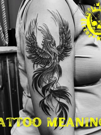 A large phoenix tattoo on the upper arm. The detailed feather work and flowing tail give the piece a sense of motion and grandeur.
