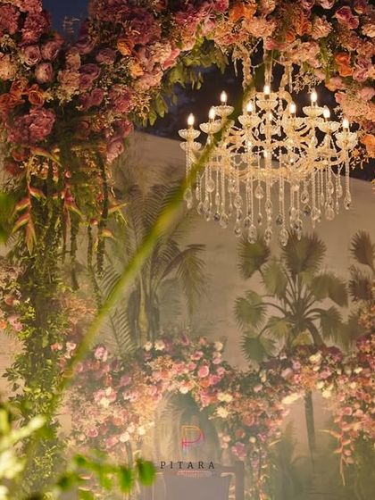 A close-up of the floral heart arch, showcasing the intricate arrangement of blooms and the beautiful glow of the chandelier.