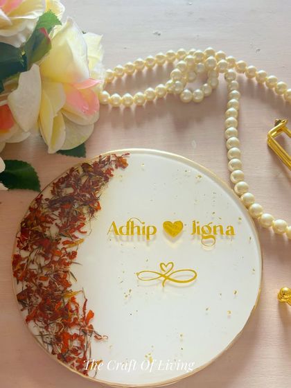 Preserving petals, holding memories. This simple and elegant resin plate features a crescent of preserved saffron-colored flowers, personalized with the couple's names.