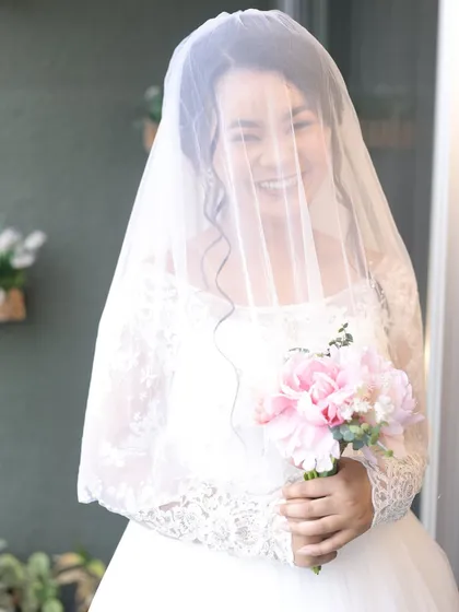 A joyful moment captured through the veil. The bride's happy smile shines through, and her soft, radiant makeup enhances her natural beauty without being overpowering.