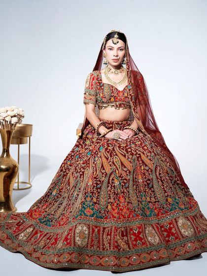 A full view of a magnificent maroon bridal lehenga with detailed paisley embroidery. This is a timeless piece that creates a stunning silhouette.