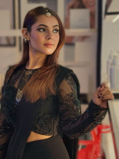 This shot showcases the full festive attire, with makeup designed to complement the dark, elegant outfit.