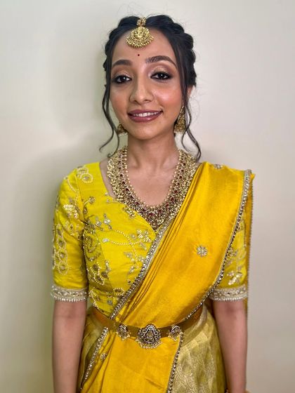 This bride shines in a bright yellow saree. Her makeup is fresh and luminous, with defined eyes and a natural lip color that lets her smile be the focus.