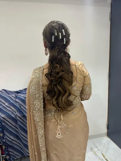 A beautiful hairstyle for a reception or sangeet. This wavy ponytail is adorned with pearl clips, adding a touch of elegance.