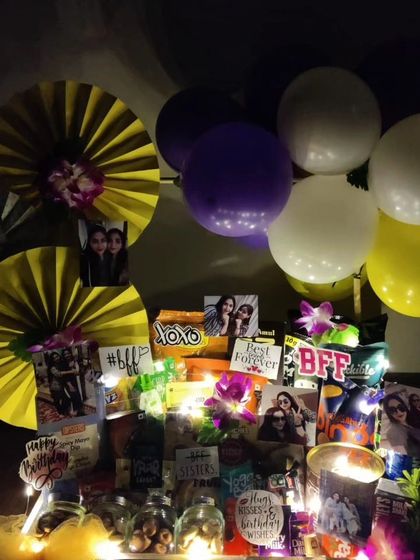 This birthday hamper for a best friend is designed to glow. It's packed with snacks, decorated with photos and paper fans, and lit with fairy lights to create a warm and celebratory mood.