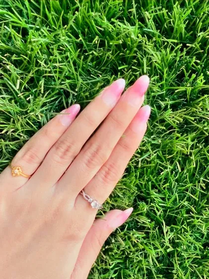 A close-up of the beautiful pink ombre nails against a vibrant green background.