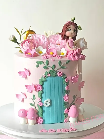 A whimsical fairy house cake with a handcrafted fairy figure, a detailed door, and delicate butterflies. The pink and teal colors create a magical and enchanting look.