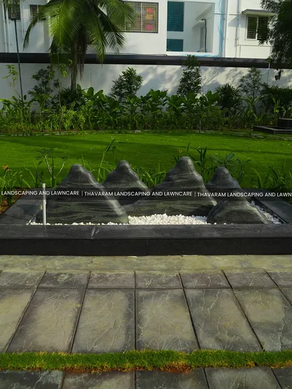 A close-up of a modern, minimalist water feature designed to look like a mountain range, with water gently flowing over the stone peaks.