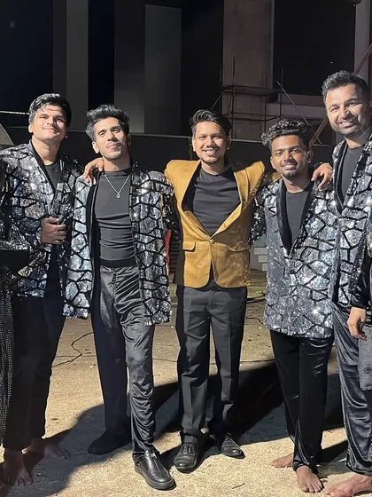 A mandatory backstage picture with our talented backup dancers in their shimmering silver and black costumes, ready to light up the stage for a destination wedding Sangeet.