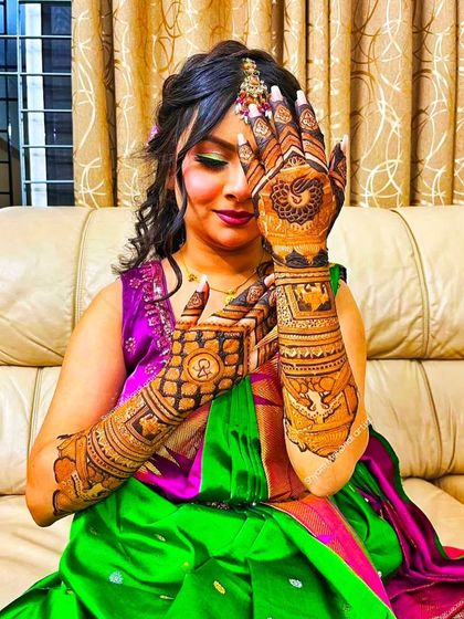 A client posing with her full bridal mehandi, which includes intricate peacock and elephant motifs.