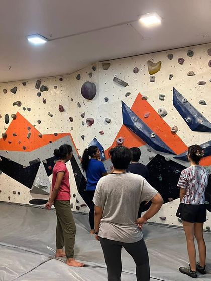 A group of women analyzing a bouldering problem on the wall. Our sessions emphasize understanding movement and route-reading, not just physical strength.