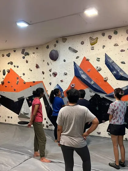 A group of women analyzing a bouldering problem on the wall. Our sessions emphasize understanding movement and route-reading, not just physical strength.