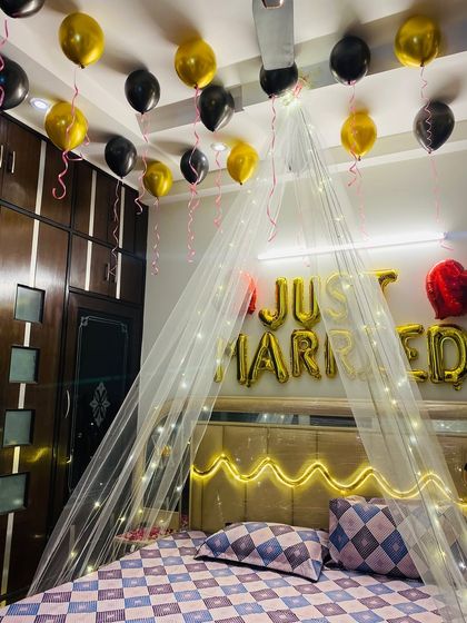 This angle captures the "Just Married" banner and the floating black and gold balloons against the dark wood wardrobe.