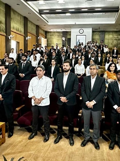 Standing with fellow judges and a hall full of law students during a moot court competition. The sheer number of participants shows the growing interest and competition in the field of law.