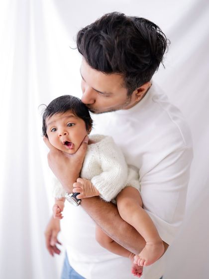 A father's love. A tender moment as a dad holds and kisses his sweet, wide-eyed baby.