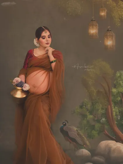 A moment of quiet reflection. The mother-to-be, holding a traditional brass pot, is captured in a serene pose against a custom-painted backdrop. My background as an architect helps me compose these frames with a deep understanding of proportion and balance.